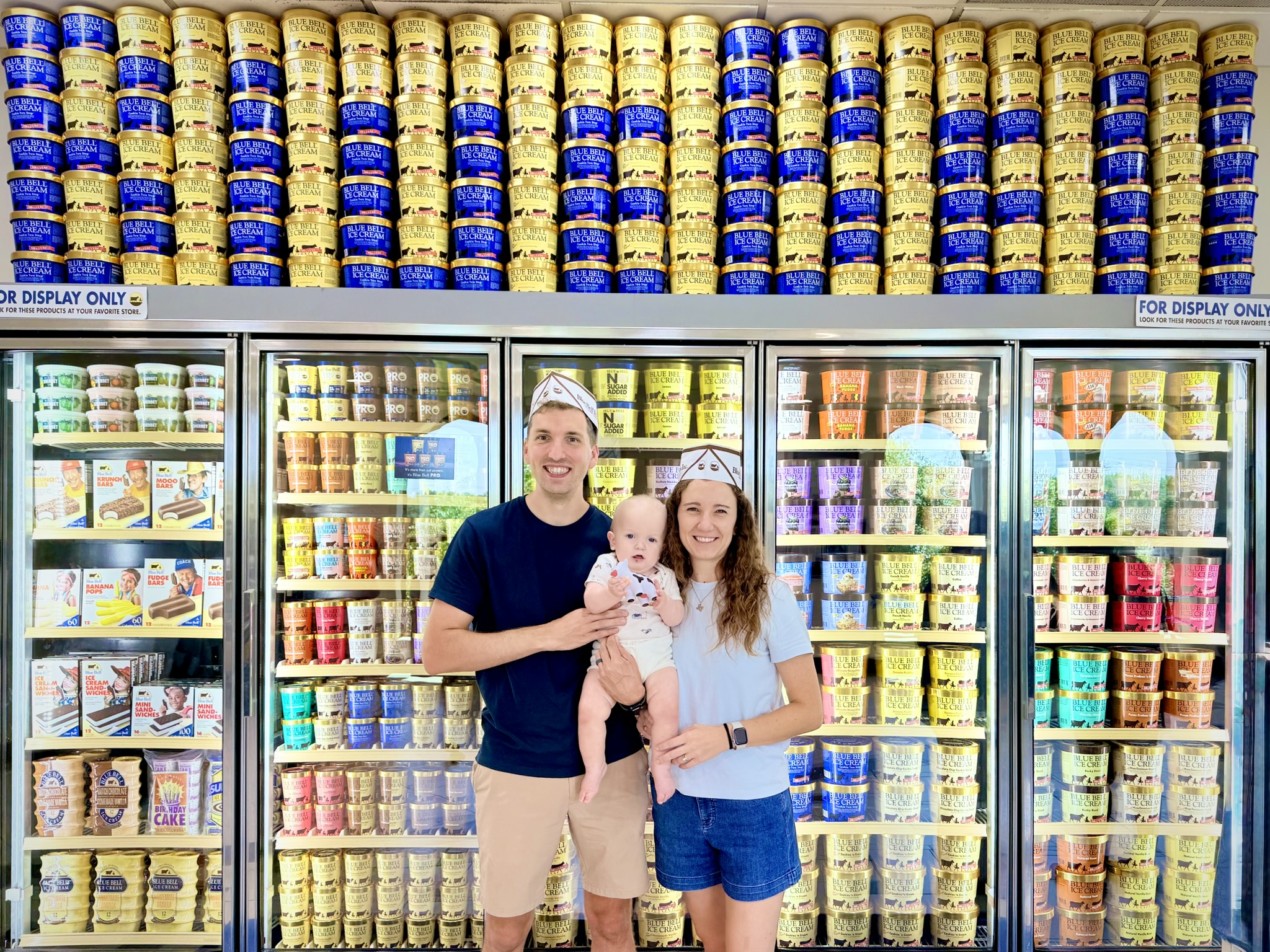 A family standing in front of a blue bell ice cream display in brenham texas
